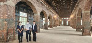 アーチが連なる煉瓦建築を前に人物が3人写っている写真