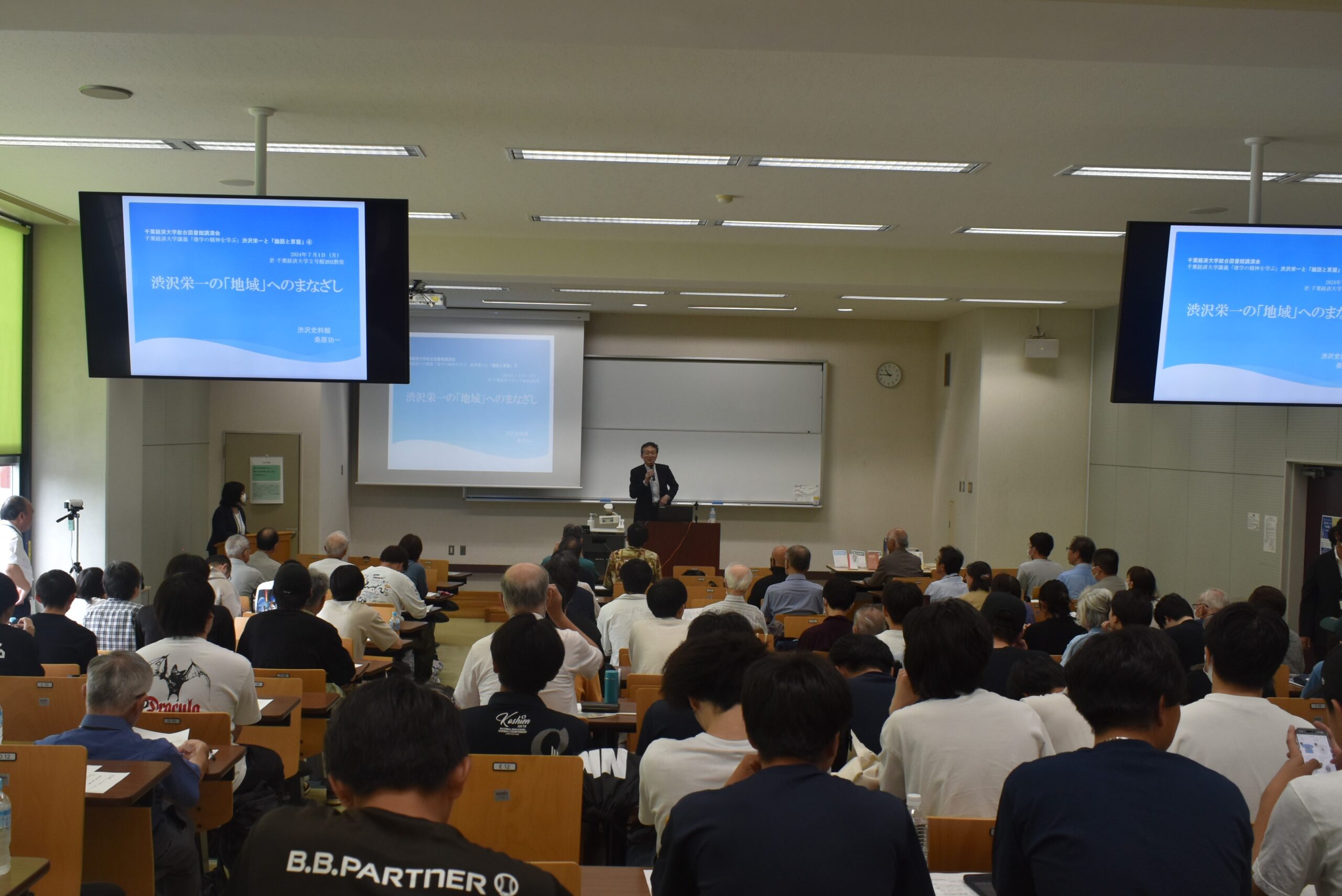 大講義室に人が多数座っている写真